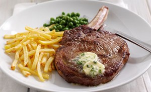 steak with chips and peas on a white plate